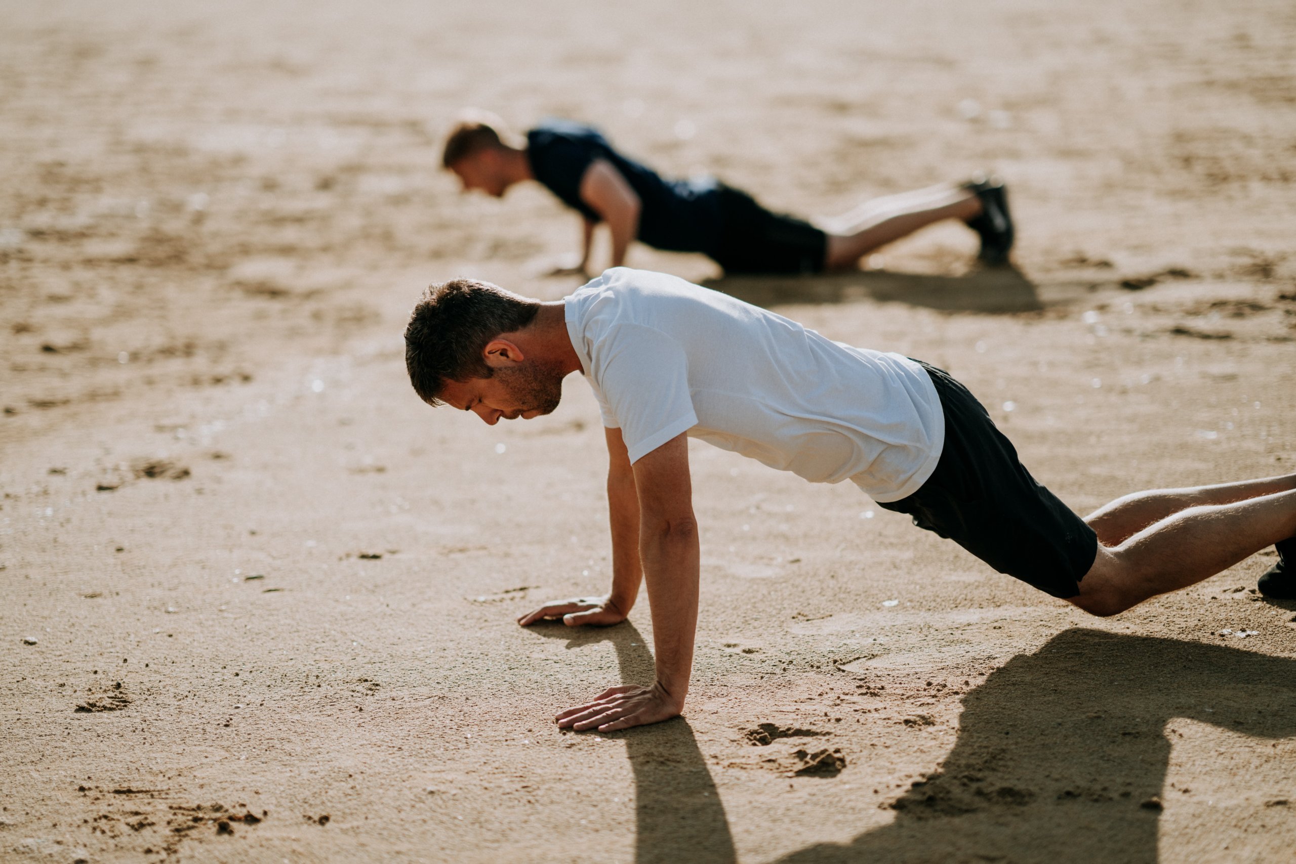 Two men are doing knee push-upsin the beach 